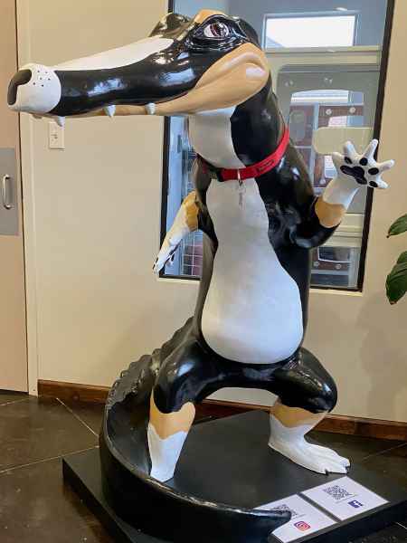 Sculpture of a cartoonish crocodile, wearing a red collar.